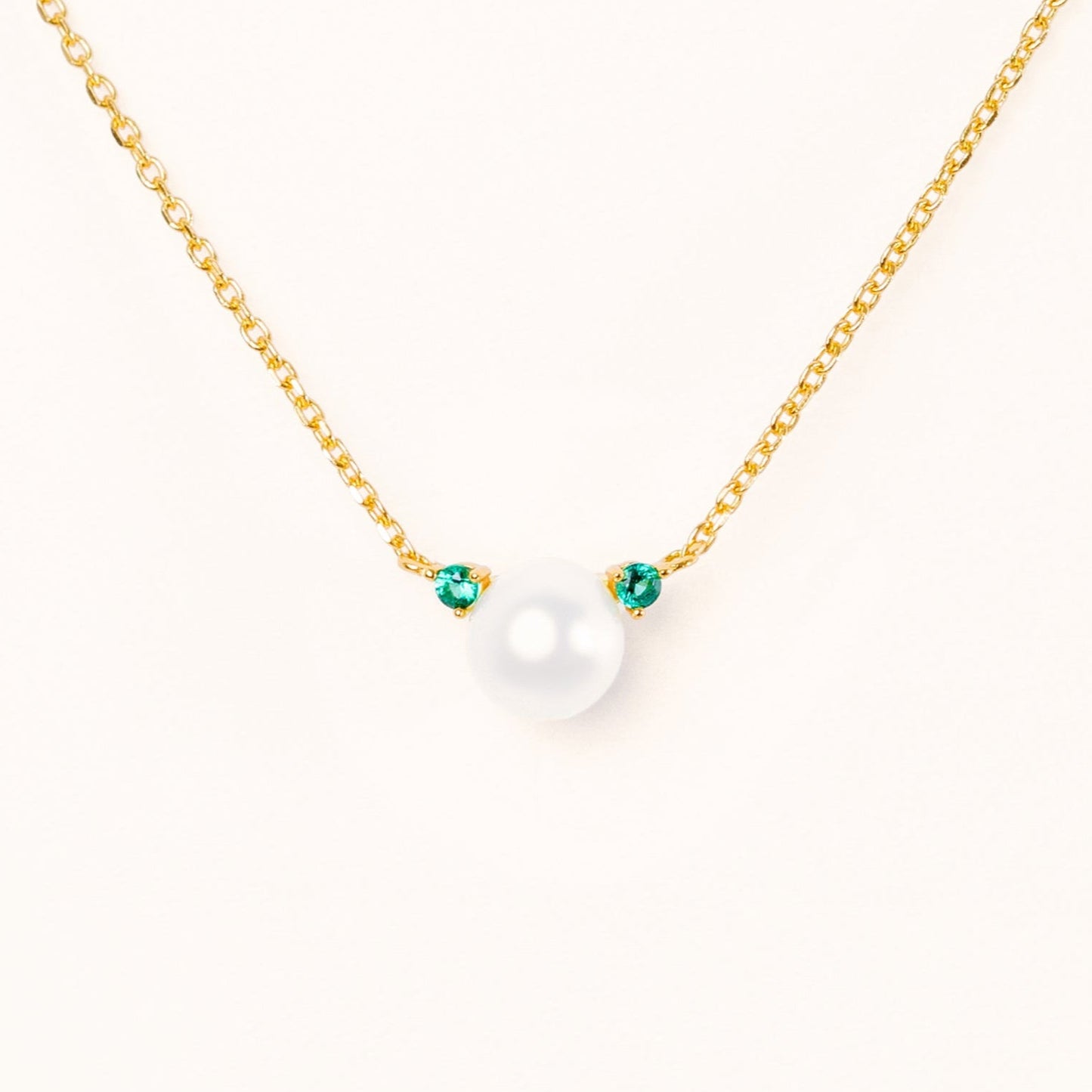 Pearl with two beautiful green emerald accents, connecting to an adjustable gold chain
