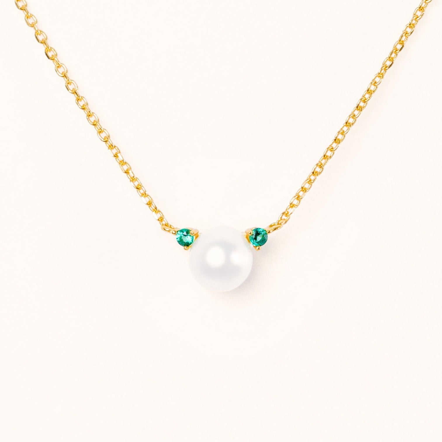 Pearl with two beautiful green emerald accents, connecting to an adjustable gold chain