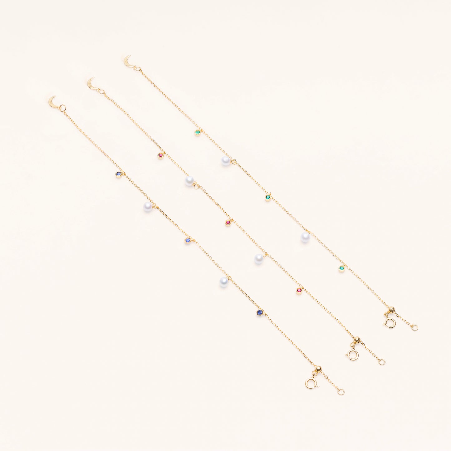 The Pearl Luna Charm Bracelet comes with the choice of lab green emeralds, blue sapphires, and red rubies