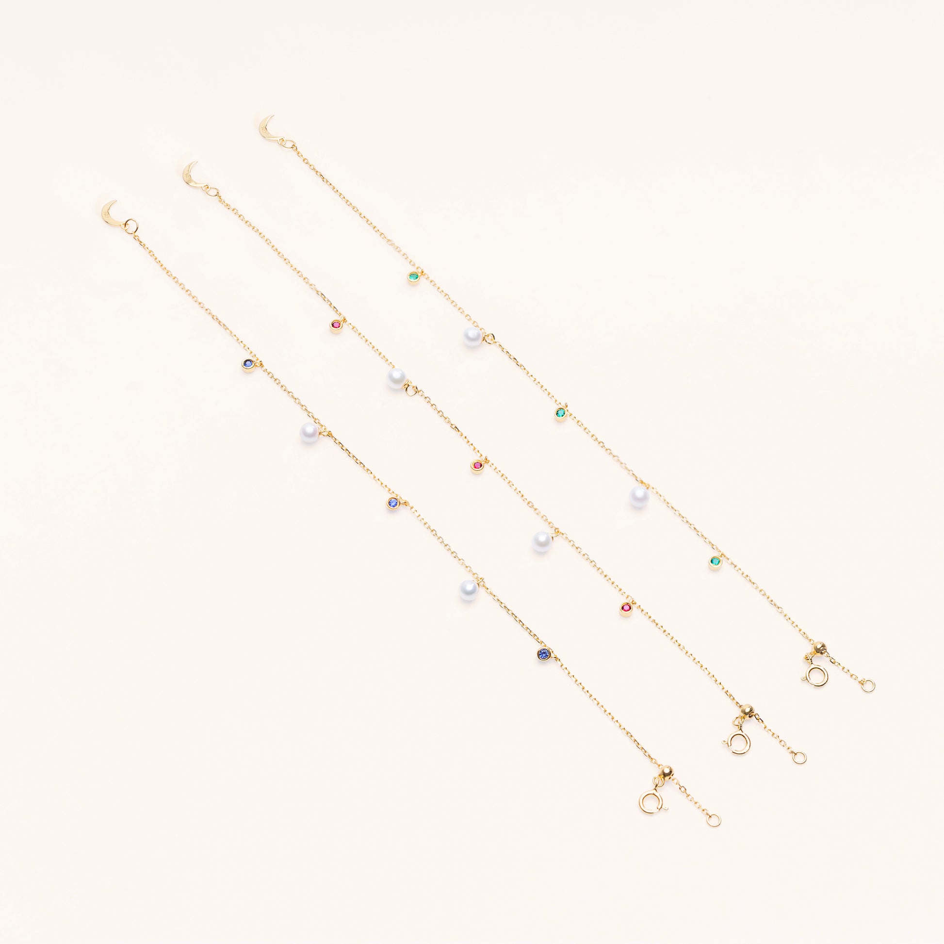 The Pearl Luna Charm Bracelet comes with the choice of lab green emeralds, blue sapphires, and red rubies