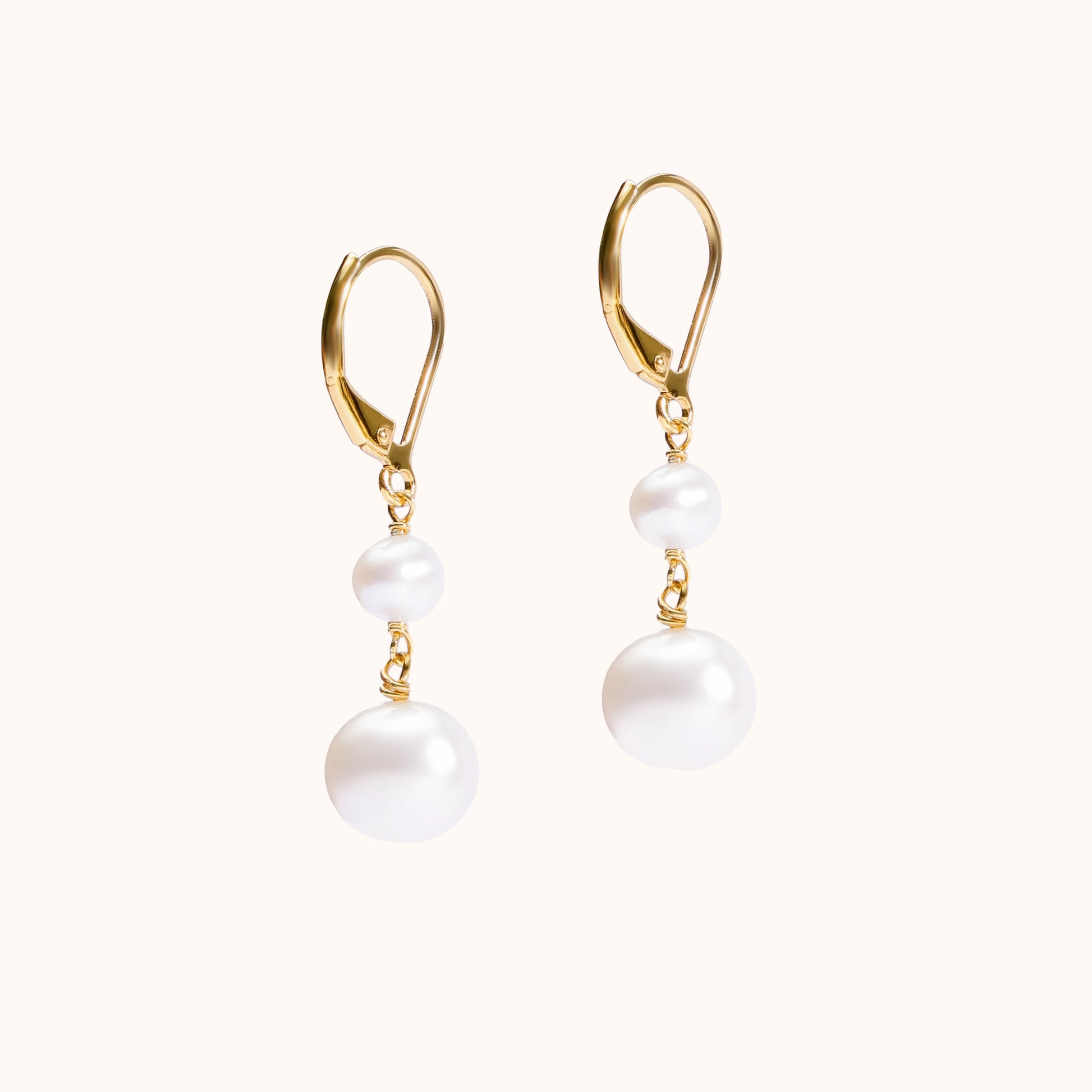 Earrings with a large pearl dangling from a smaller one