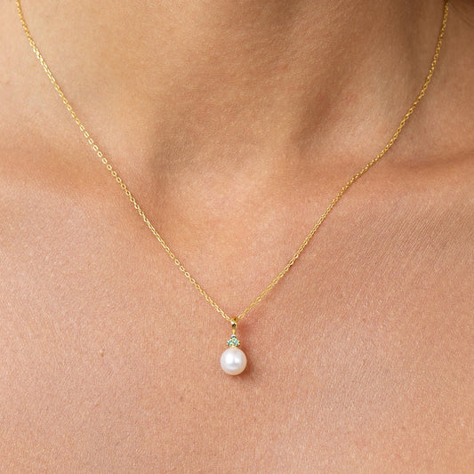 Pearl pendant with 3 emeralds on a gold chain.
