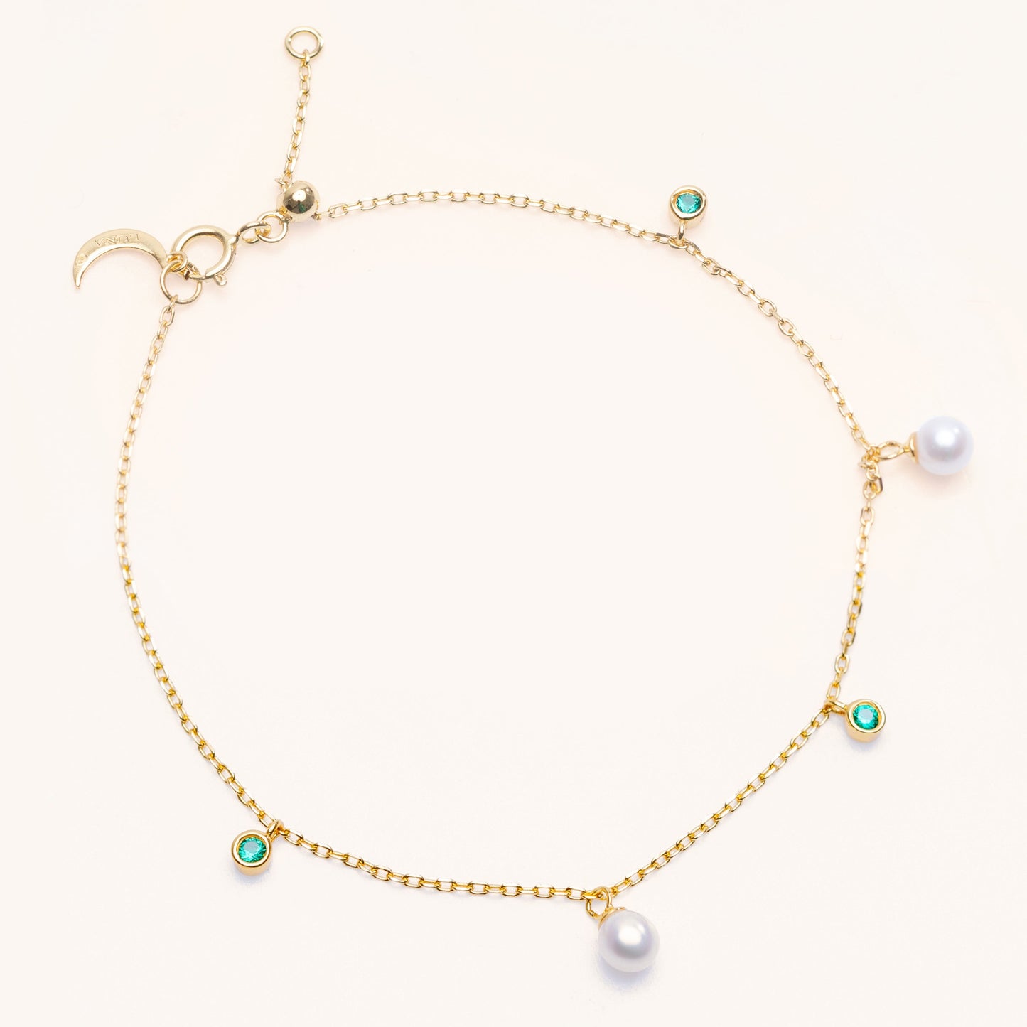 Pearl Luna Bracelet with an adjustable sliding clasp. With small round pearls and emerald charms