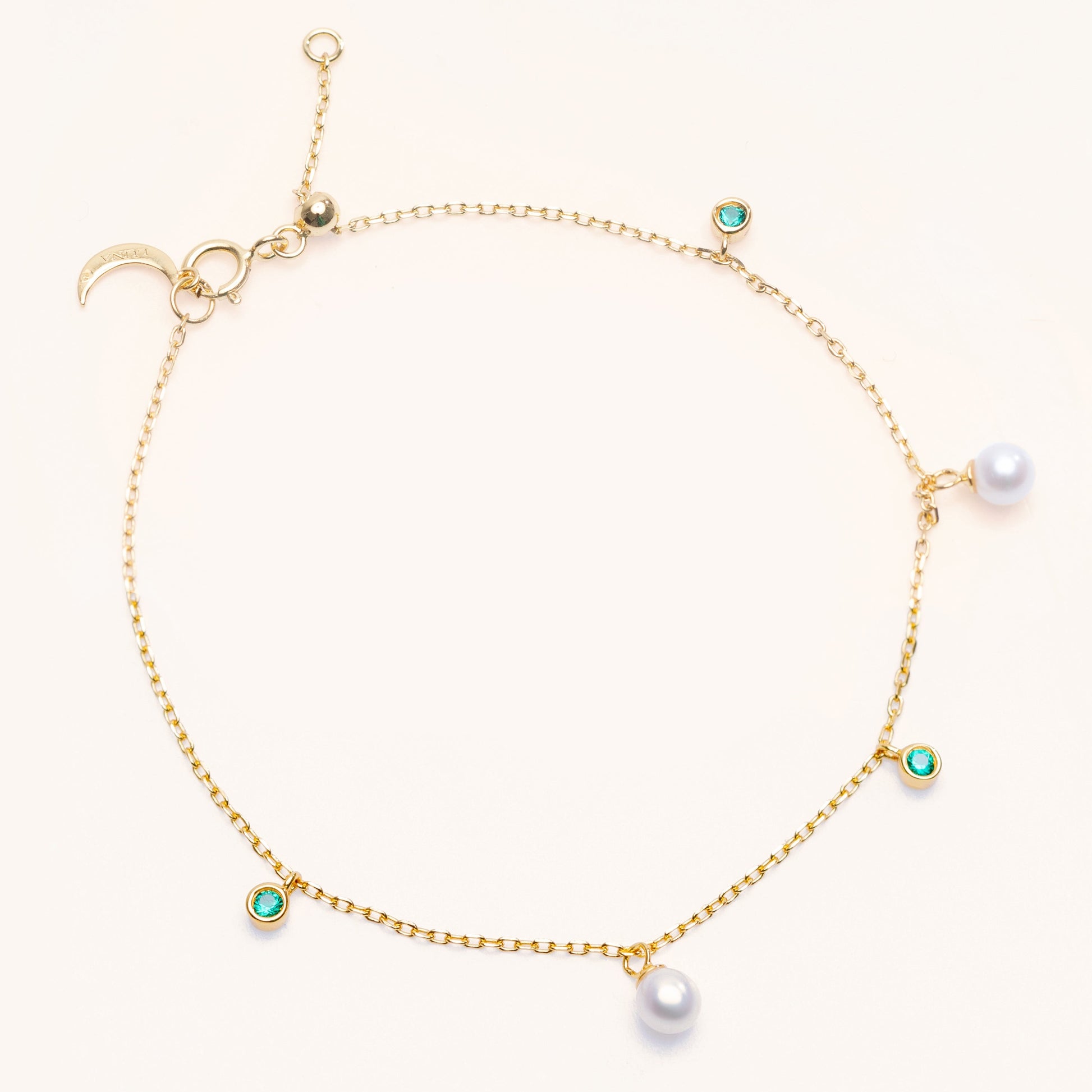 Pearl Luna Bracelet with an adjustable sliding clasp. With small round pearls and emerald charms