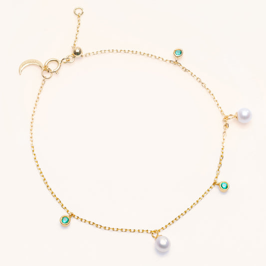 Pearl Luna Bracelet with an adjustable sliding clasp. With small round pearls and emerald charms