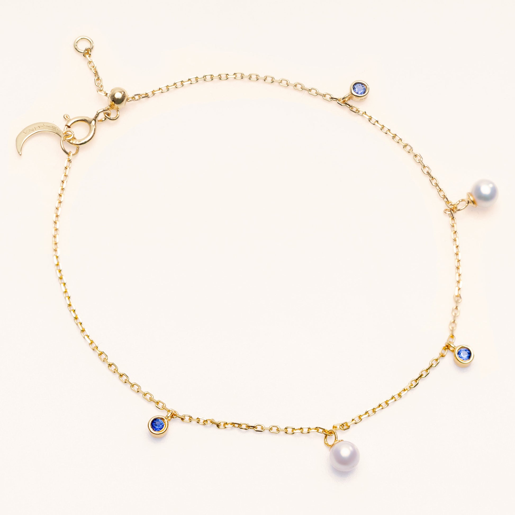 Pearl Luna Bracelet with an adjustable sliding clasp. With small round pearls and blue sapphire charms