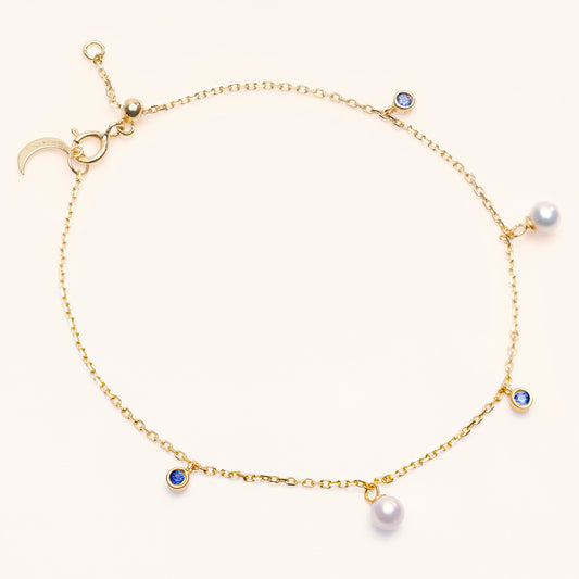 Pearl Luna Bracelet with an adjustable sliding clasp. With small round pearls and blue sapphire charms