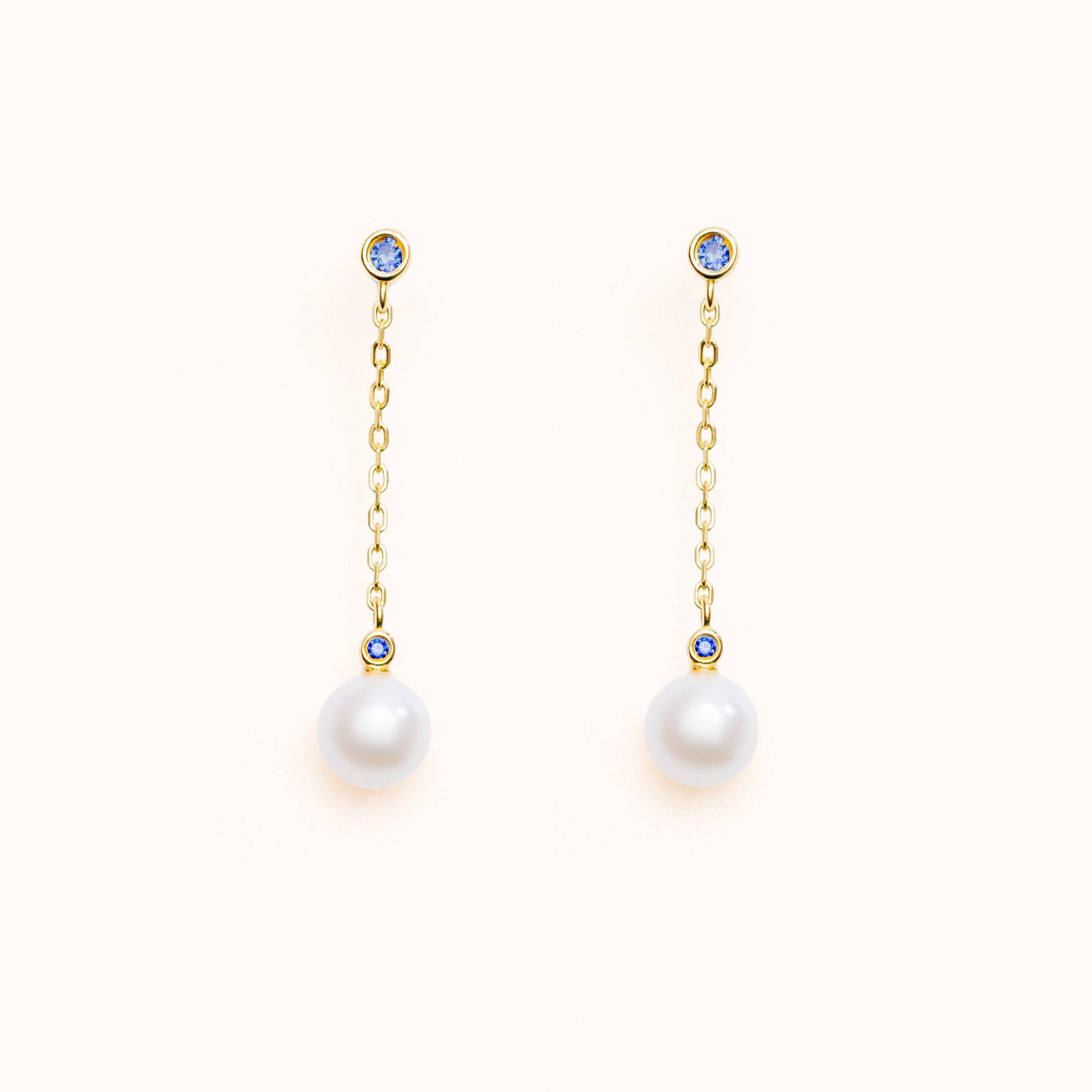 Drop earrings featuring two blue lab-grown sapphire accents and round freshwater pearls on 18k gold-plated 925 silver studs