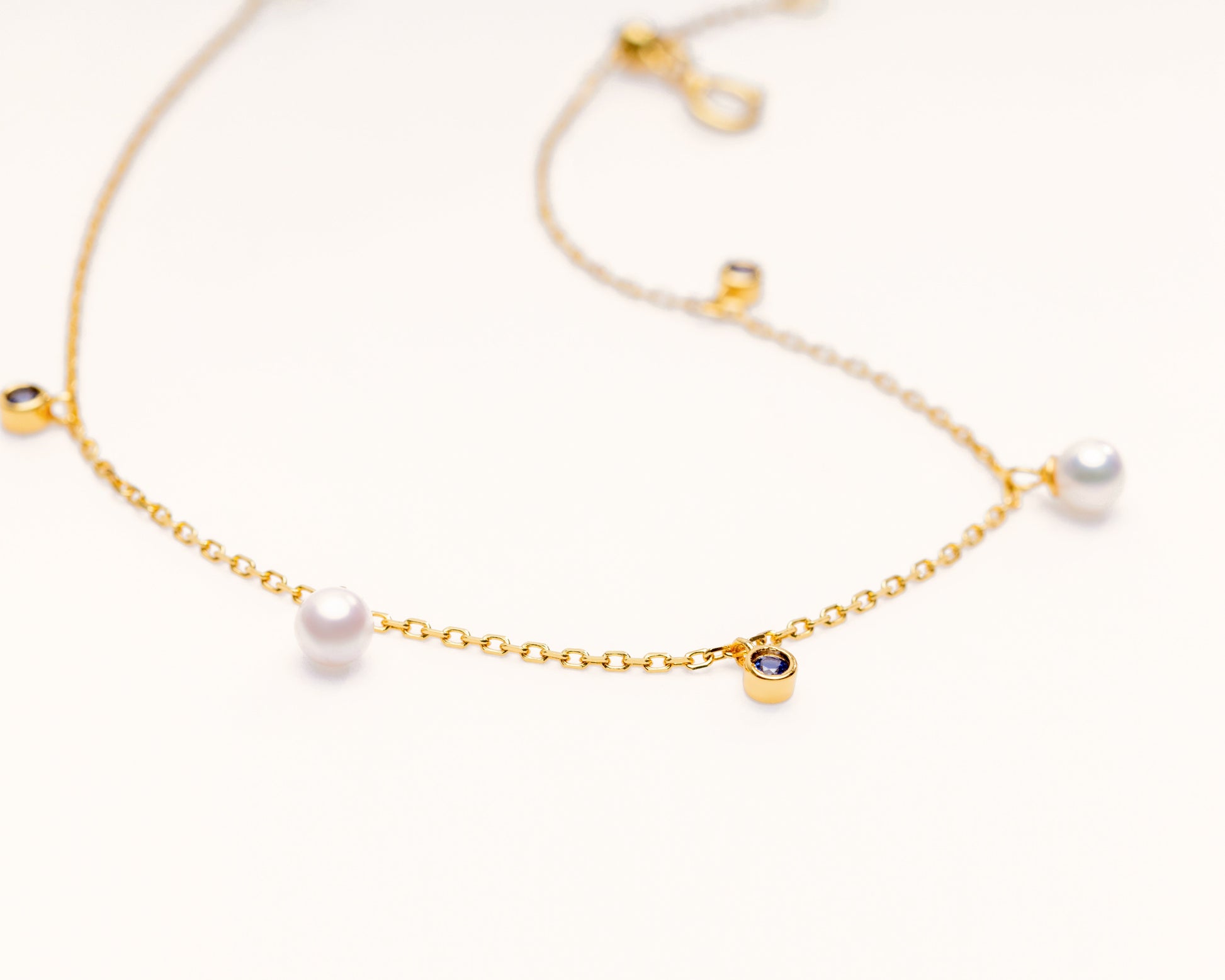 Pearl bracelet on a gold chain with dainty sapphire charms