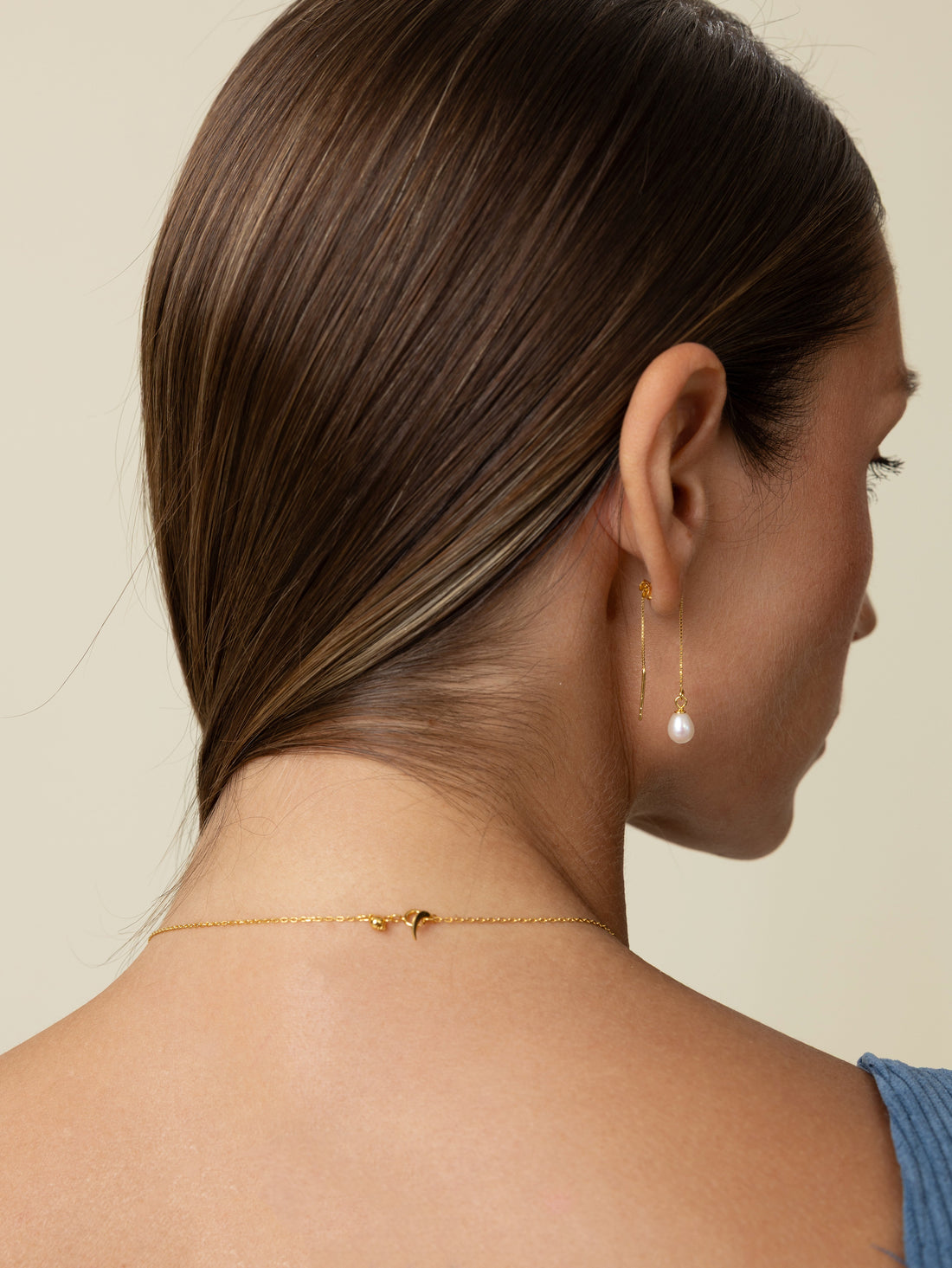 Close-up of the back of a woman's neck showing a delicate freshwater pearl necklace and its 18k gold-plated sterling silver clasp