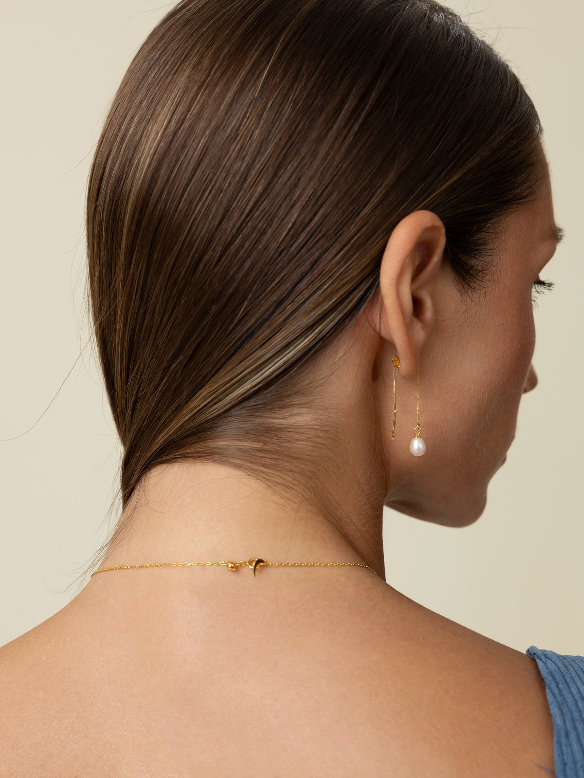 Close-up of the back of a woman's neck showing a delicate freshwater pearl necklace and its 18k gold-plated sterling silver clasp
