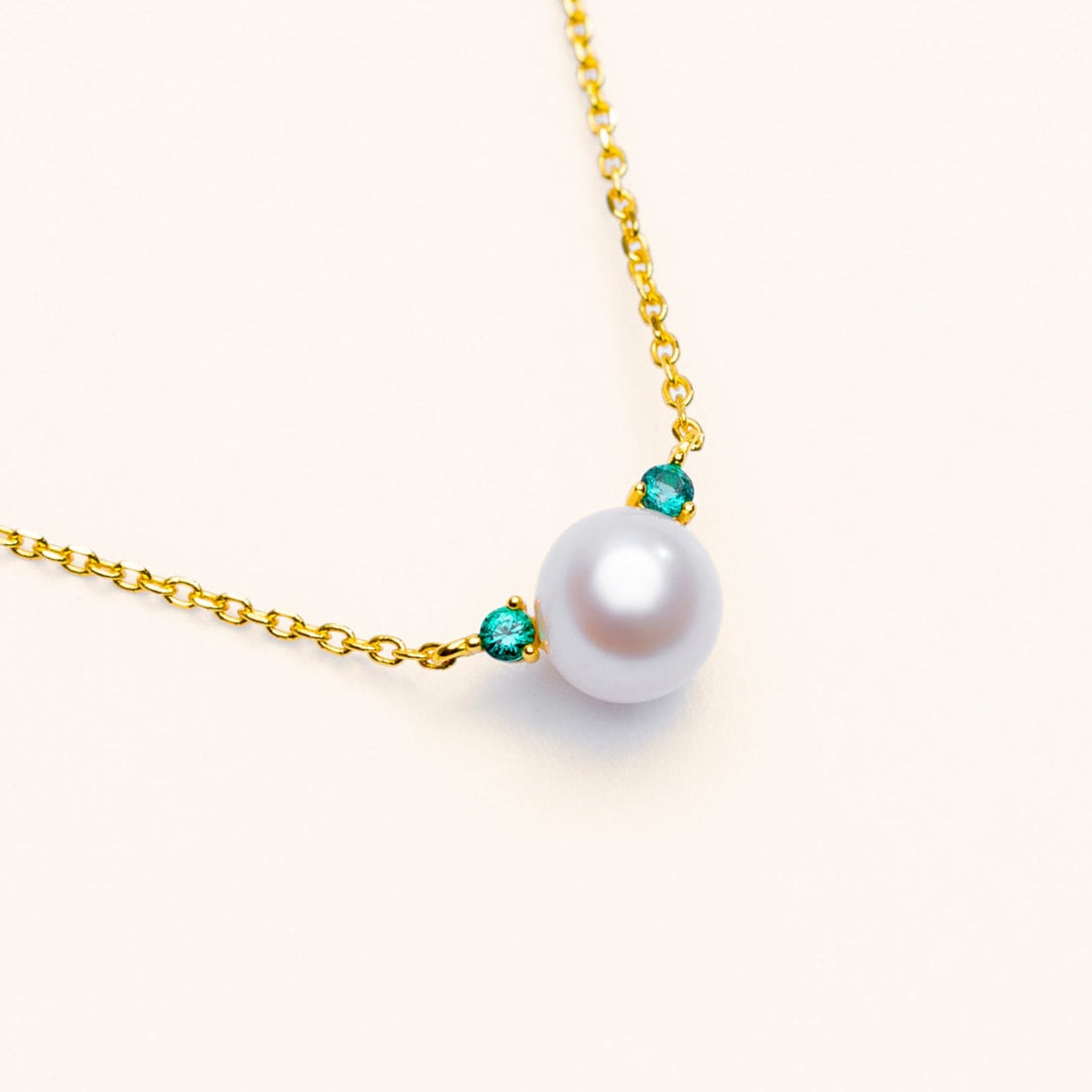 Freshwater pearl pendant necklace with a small green lab-grown emerald accent on an 18k gold-plated sterling silver chain